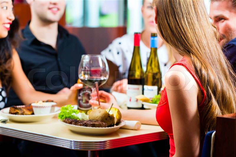 Friends or couples eating fast food and drinking beer and wine in a American fast food diner, stock photo