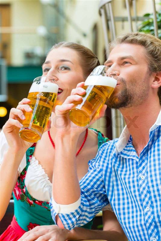 Young couple in traditional Bavarian Tracht in restaurant or pub with beer, stock photo