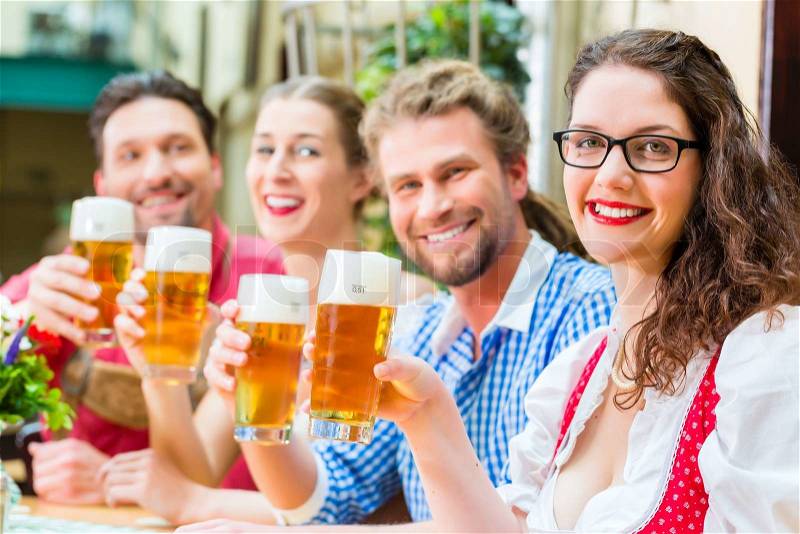 Friends in traditional Bavarian Tracht in restaurant or pub with beer in Bavaria, Germany, stock photo