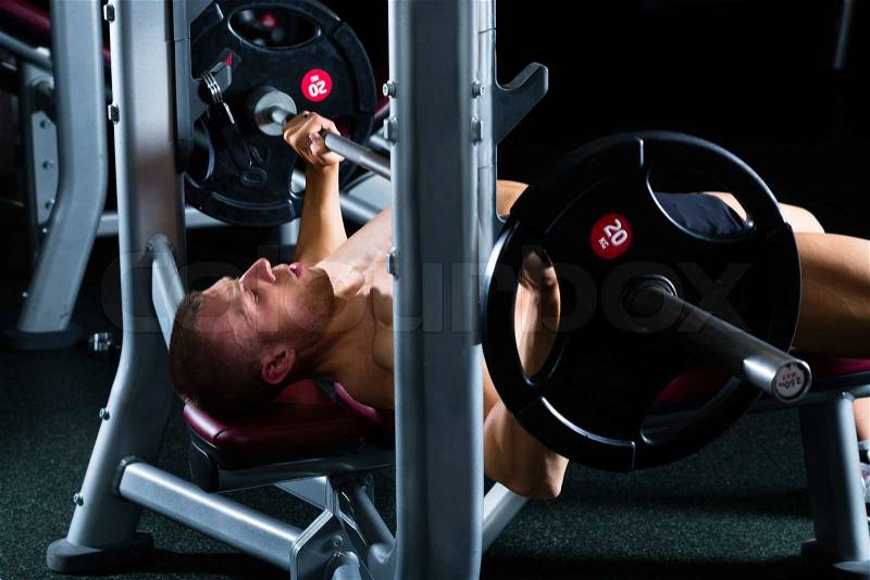Strong man - bodybuilder with dumbbells in a gym, exercising with a dumbbell, stock photo