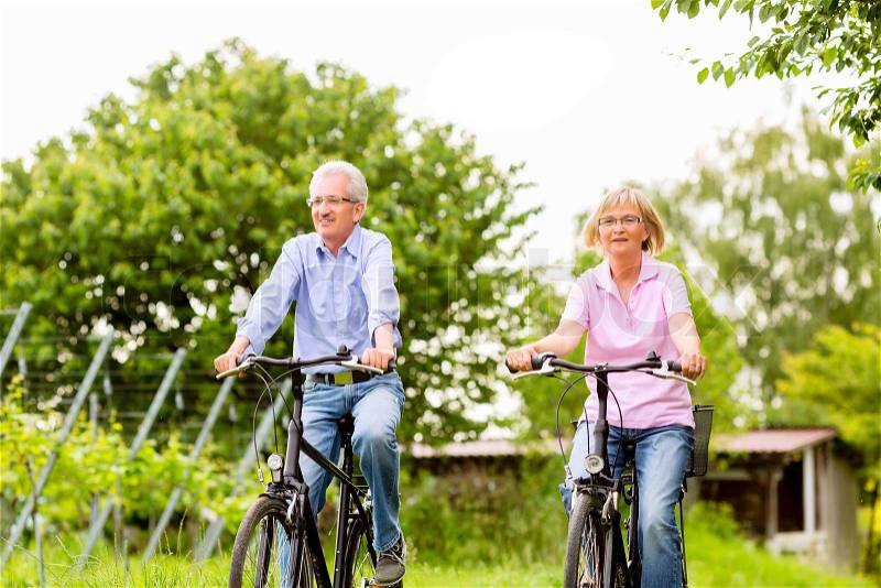 Senior Man and woman exercising with bicycles outdoors, they are a couple, stock photo