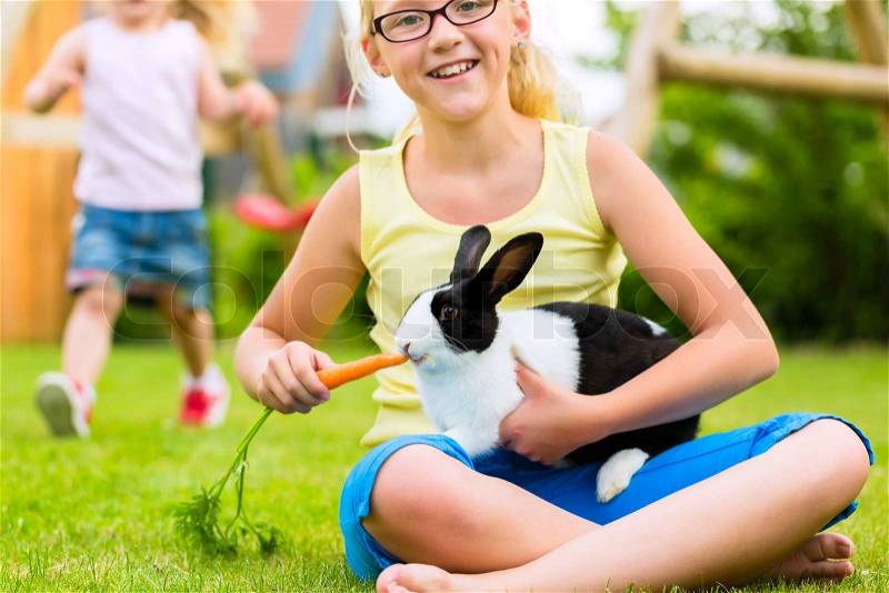 Happy Girl or daughter with her rabbit or bunny pet at home in the garden, stock photo