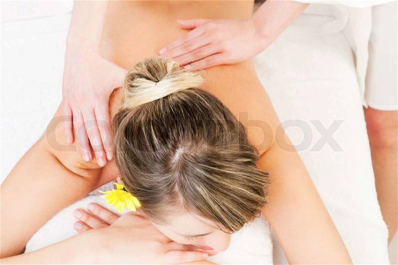 Beautiful woman having a wellness back massage and feeling visibly good about it, stock photo