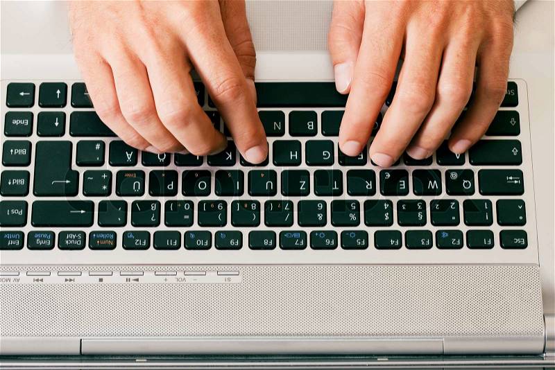 Man (only hand to be seen) using a computer keyboard typing, stock photo