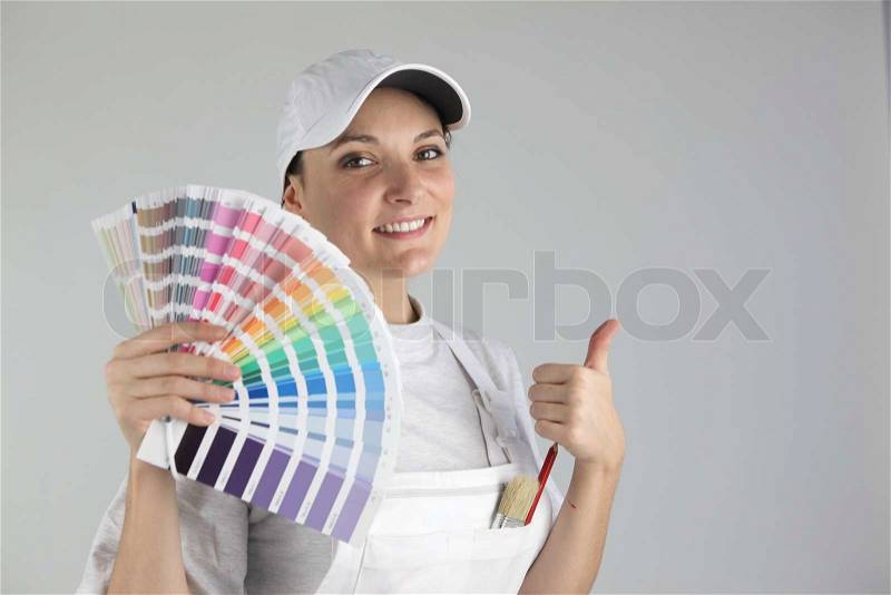 Smiling woman painter holding swatches, stock photo