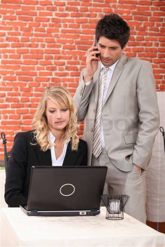 Businessman and assistant watching laptop, stock photo