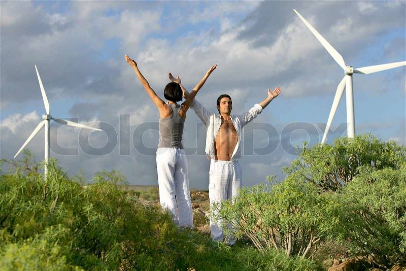 Couple stood in wind farm, stock photo