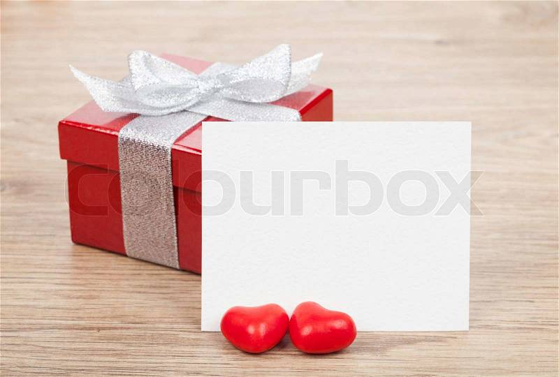 Blank valentines greeting card and small red gift box on wooden table, stock photo