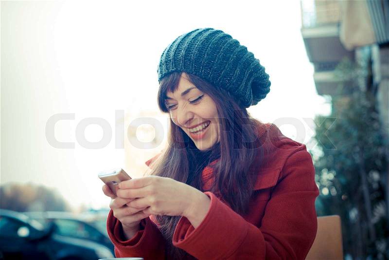 Beautiful woman red coat cellphone sitting bar winter, stock photo