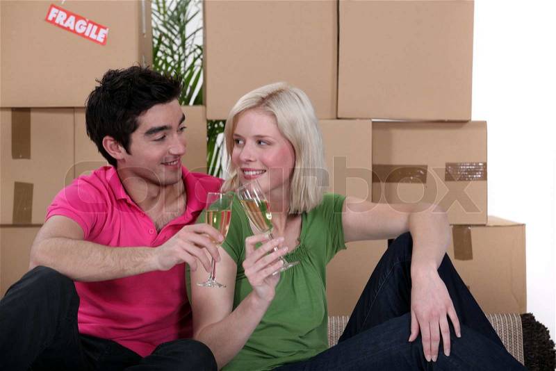 Couple having a celebratory drink on moving day, stock photo