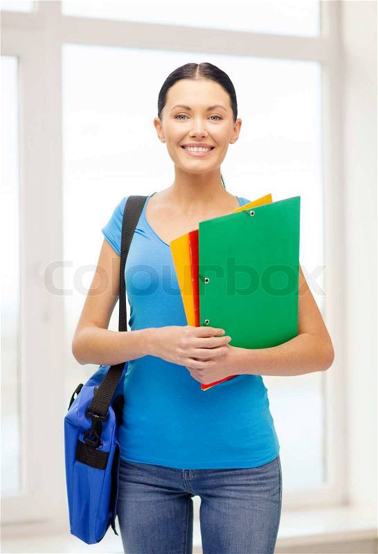 Education and school concept - smiling female student with folders and bag at school, stock photo