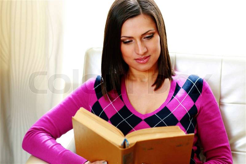 Portrait of a young beautiful woman reading a book at home, stock photo