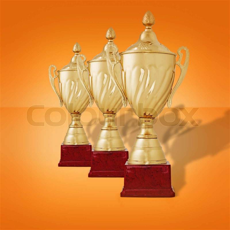 Receding row of gold trophy cups with lids on wooden plinths waiting to be awarded to the winners of a championship or competition on an orange background, stock photo