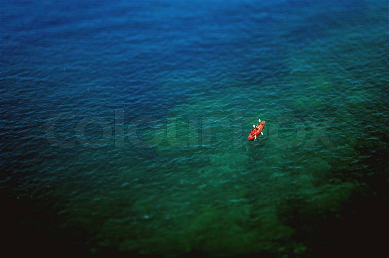 Couple kayaking in wide blue sea as seen from above. Tilt-shift lens used, stock photo