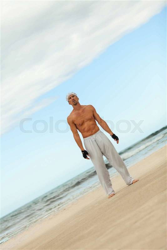 Man is jumping sport karate martial arts fight kick jump beach summertime, stock photo