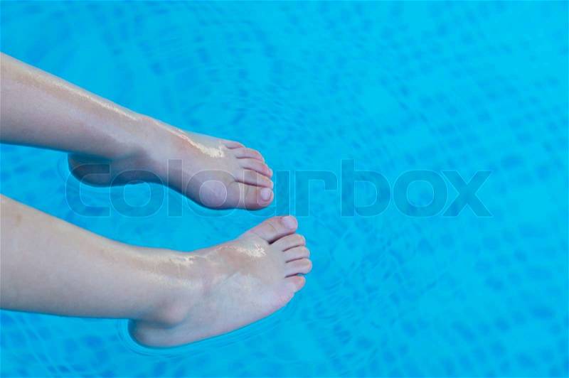 Feet refreshing in swimming pool in summer, stock photo