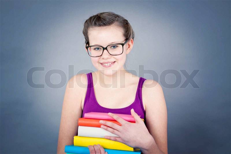 Silly smiling schoolgirl with glasses and lots of books having fun, stock photo