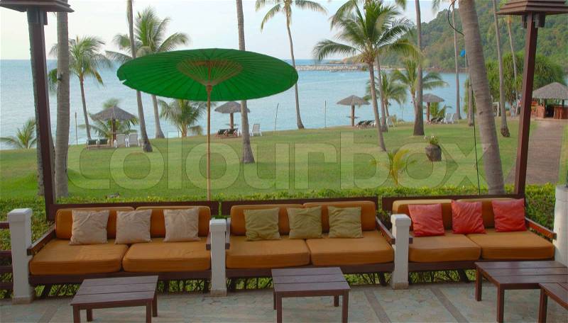Outdoor table and sofas on terrace overlooking sea, stock photo