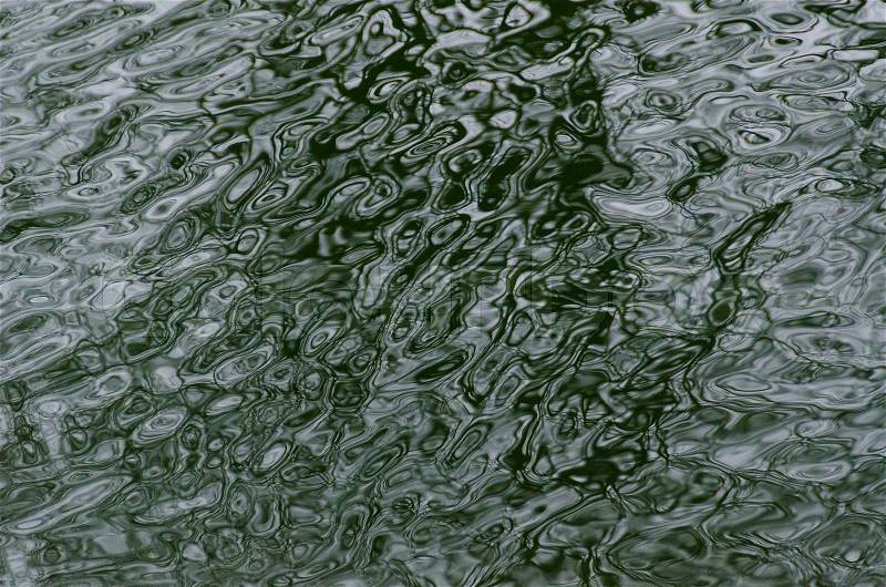 Complex green water ripple background pattern with shadow from a tree in winter, stock photo