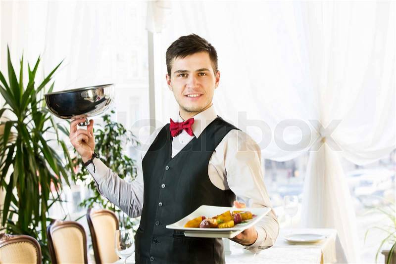 Waiter with a tray of food in the restaurant hall, stock photo