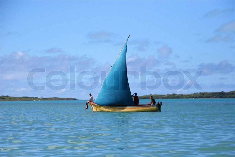 Oldrig sailing boat with blue sail in the light wind with three fisherman on board, stock photo