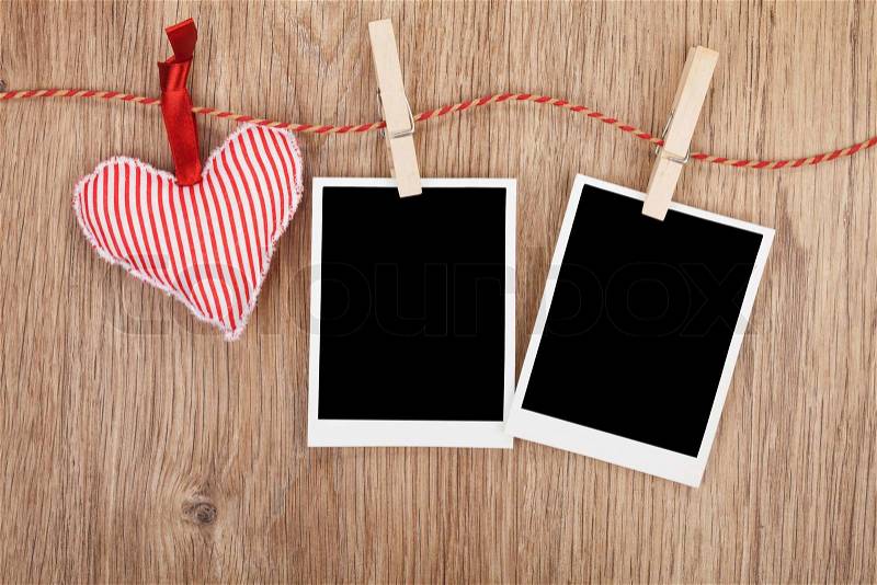 Blank instant photos and red heart hanging. On wooden background, stock photo