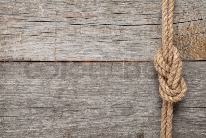 Ship rope knot on old wooden texture background, stock photo