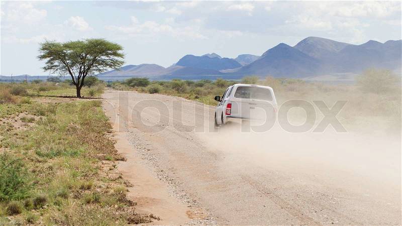 Car driving a gravel road in the Namib desert, Namibia, stock photo