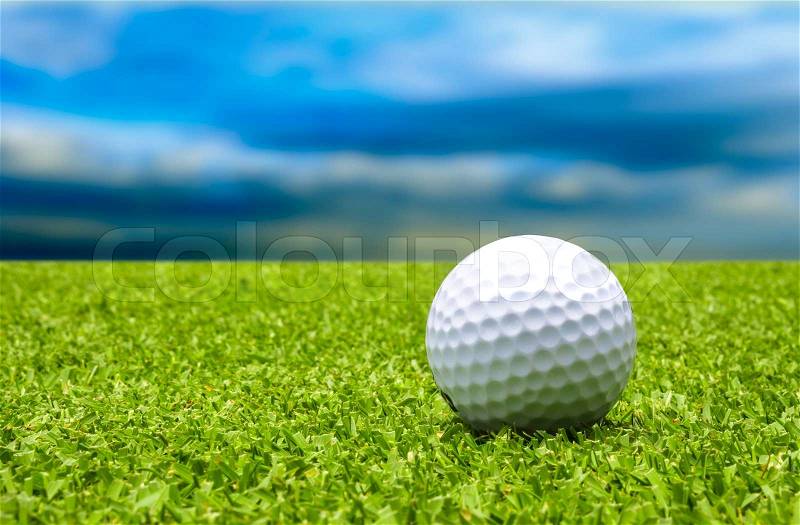 Golf ball on tee with blue sky, stock photo