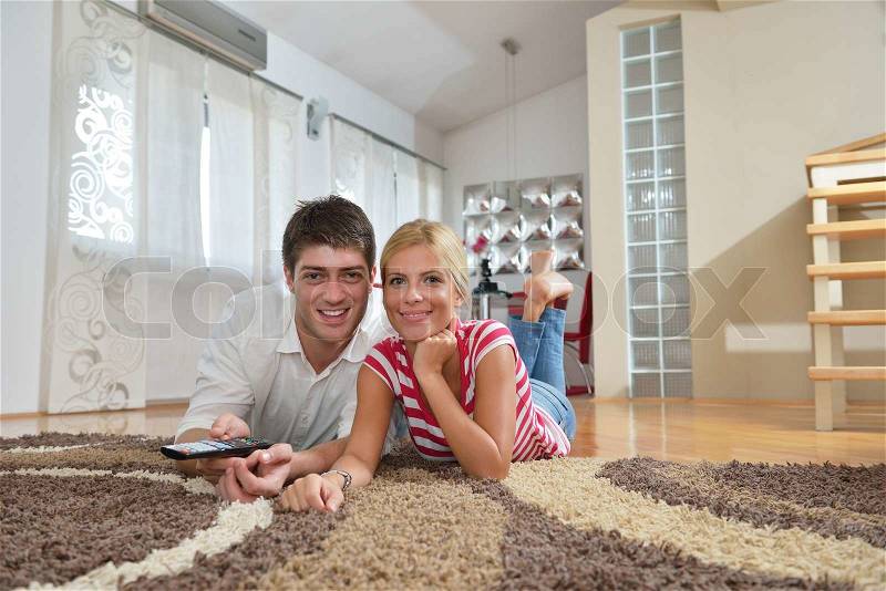 Relaxed young couple watching tv at home in bright living room, stock photo