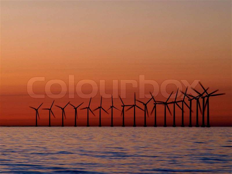 Row of water based windmills in front of sunset coloured sky. Long shuttertime to show a little movement in the arms of the mills, stock photo