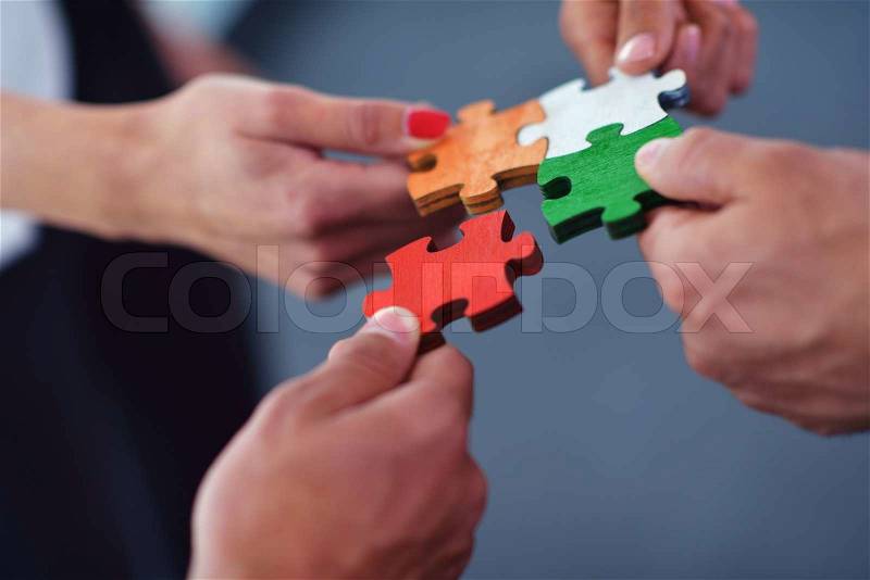 Group of business people assembling jigsaw puzzle and represent team support and help concept, stock photo