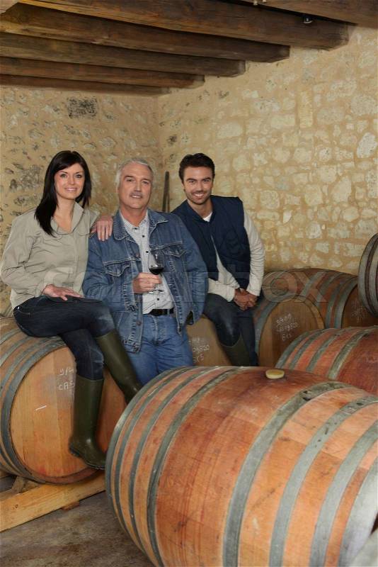 Three wine producers smiling in cellar, stock photo