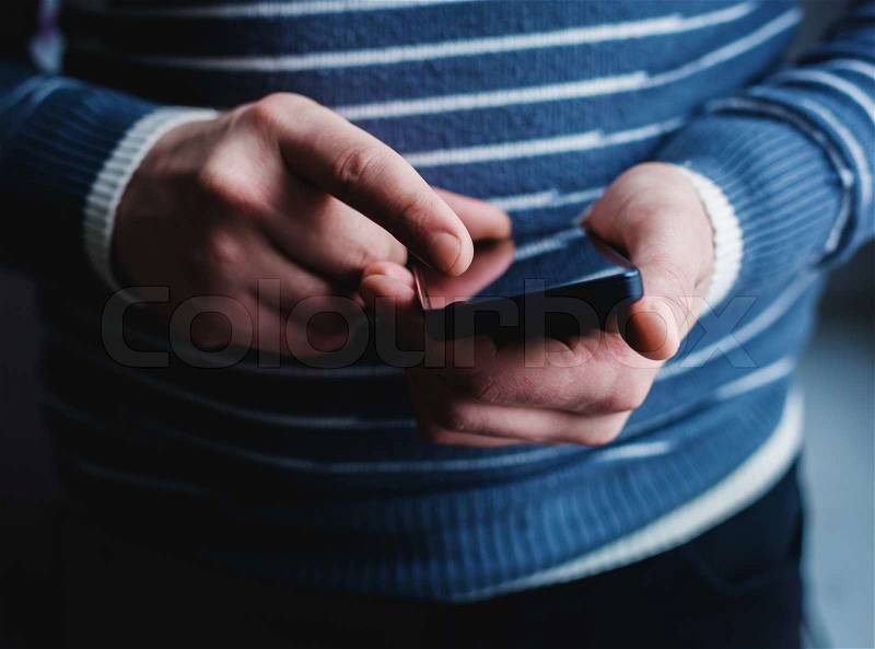 The man is using a smartphone. Modern mobile phone in hand, stock photo
