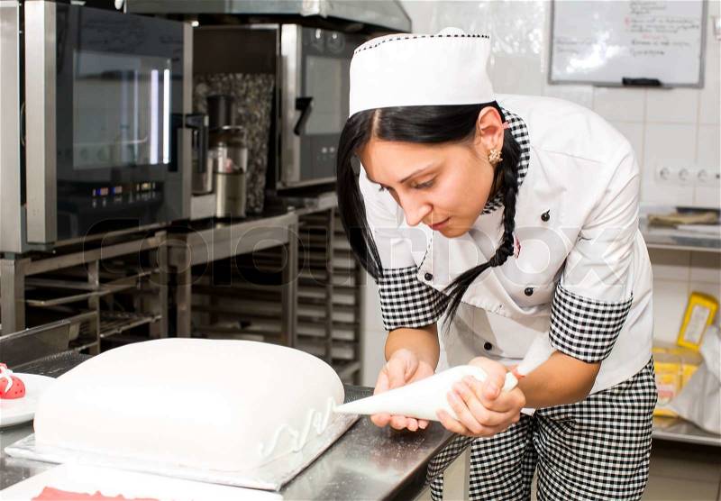 Pastry chef decorates a cake in a candy store, stock photo
