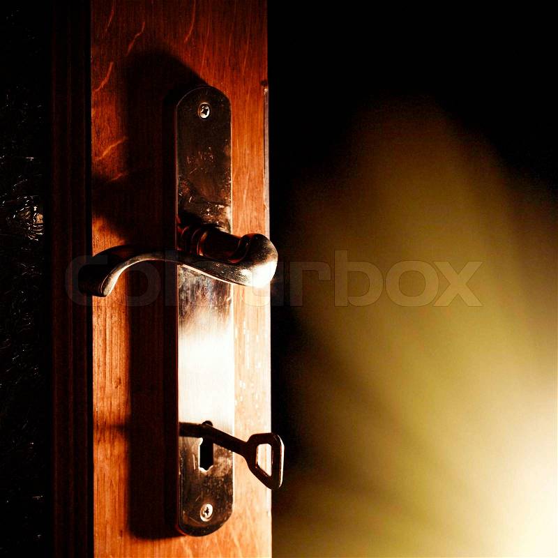 Open door with key into the dark room with light, stock photo