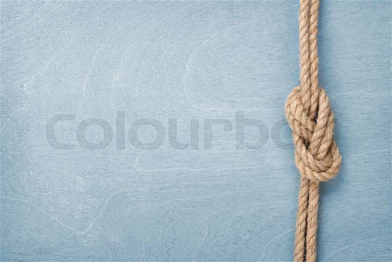 Ship rope knot on blue wooden texture background, stock photo