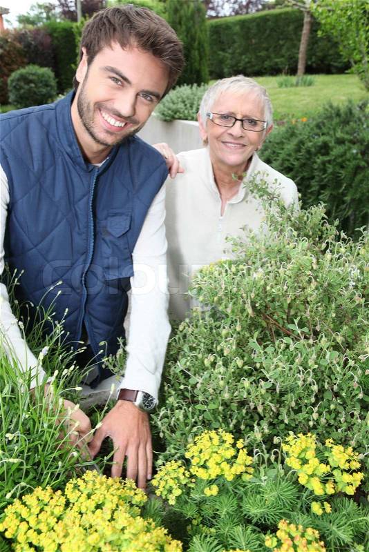 Young man gardening with older woman, stock photo