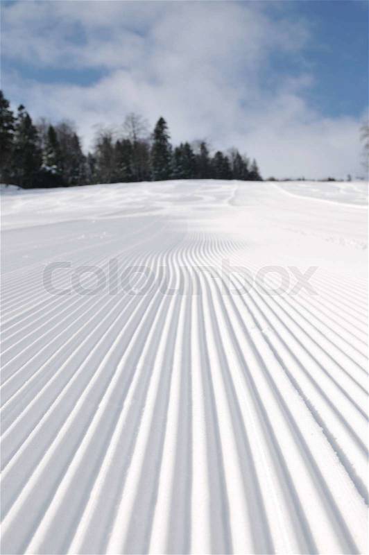 Tracks on ski slopes in snow at beautiful sunny winter day with blue sky, stock photo
