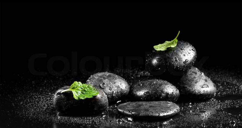 Zen stones with mint leaves on a black background, stock photo