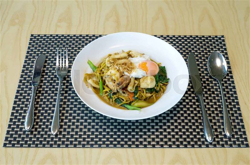 Fried noodles with sea food, vegetables and poached egg, thai food, stock photo