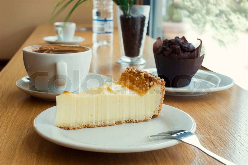 Cheesecake, muffin, coffee and mineral water on a table, stock photo