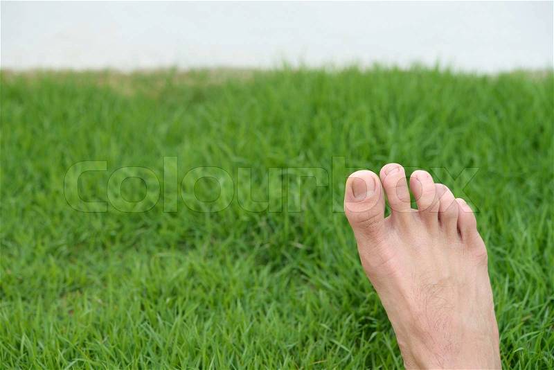 Single foot on the right of green grass, stock photo