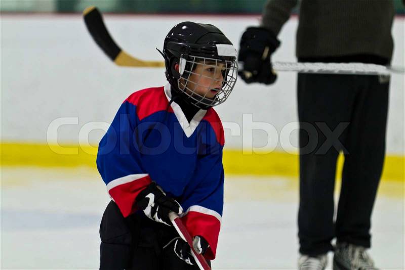 Child ice hockey player at practice with coach watching on, stock photo