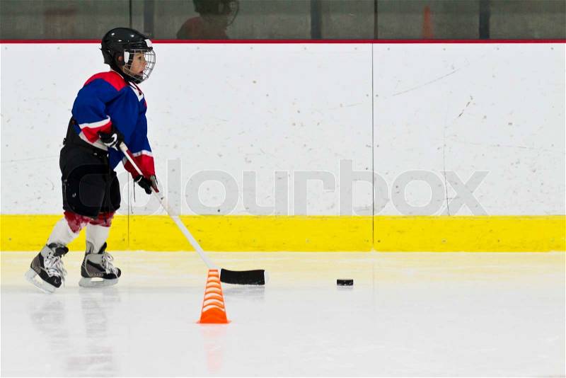 Child practices stickhandling at ice hockey practice, stock photo