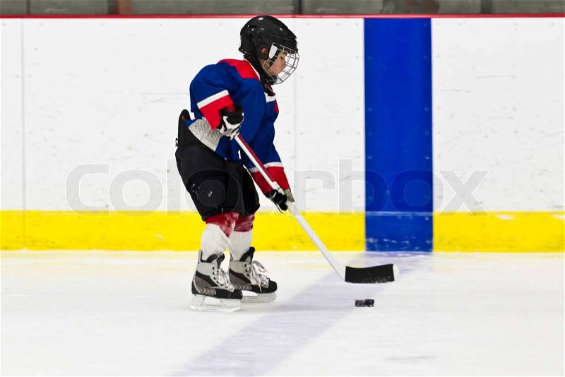 Boy skating with the puck at ice hockey practice, stock photo