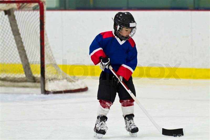 Child skating with a puck at ice hockey practice, stock photo