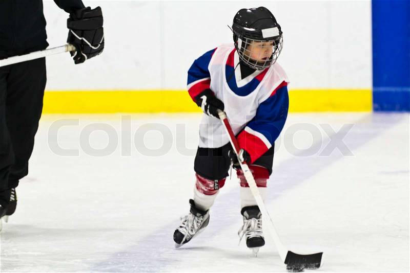 Child skating with a puck at ice hockey practice, stock photo
