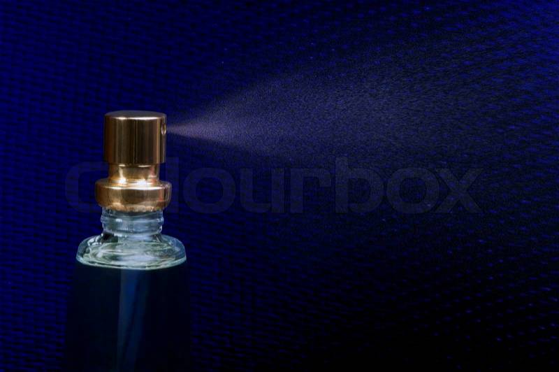 Perfume spray on blue background. Studio shot, stock photo