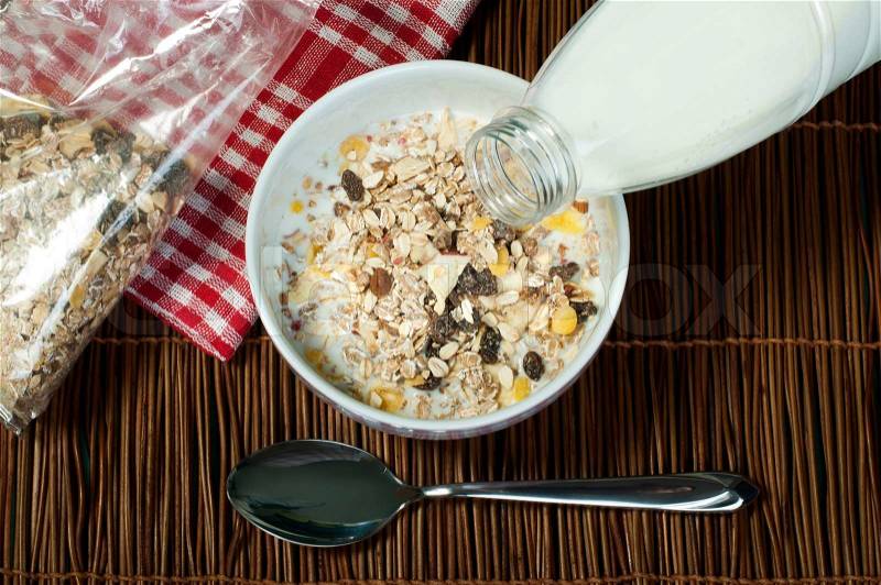 Muesli breakfast in package.Bottle milk and spoon. Pouring milk in a bowl, stock photo